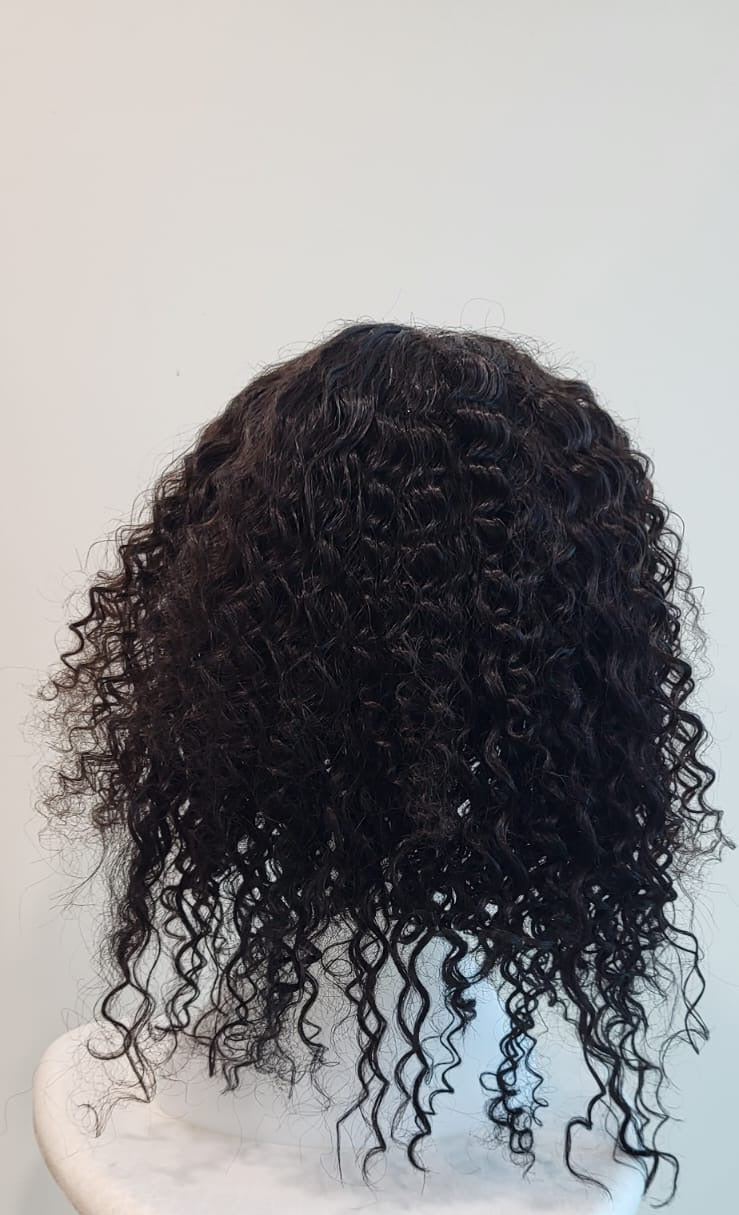 Black curly wig on a white chair against a light gray background