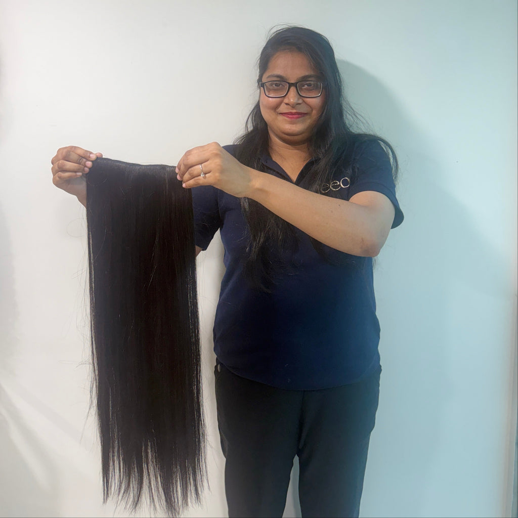 Person holding a long black hair extension against a white background