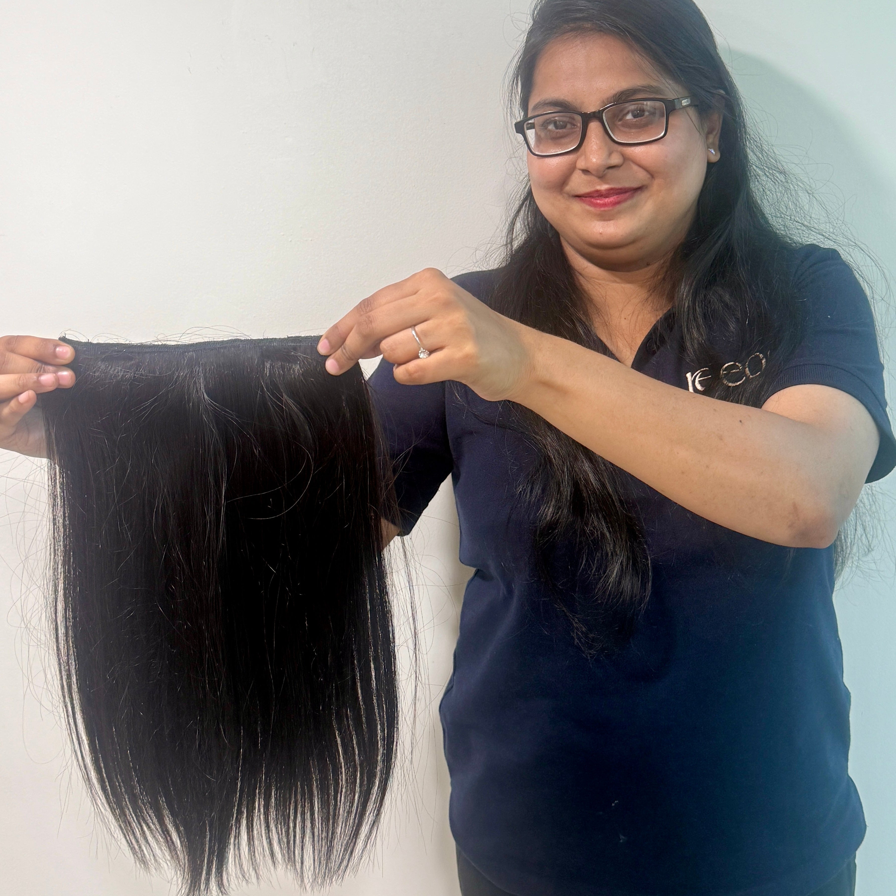 Woman holding a bundle of black hair extensions against a white background