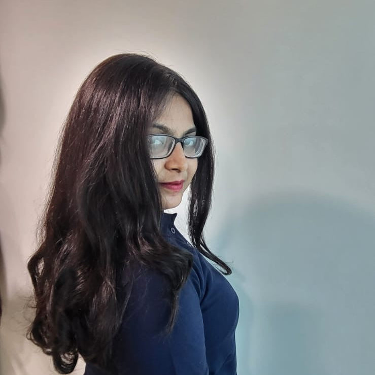 Person wearing a navy blue shirt and glasses, holding a yellow object against a plain background